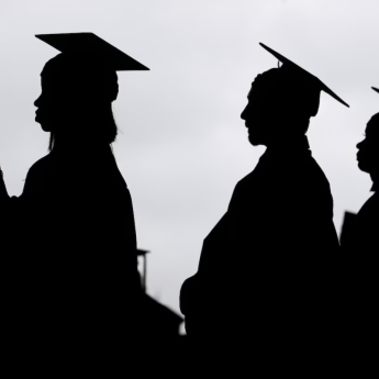 Four graduates stand in cap and gown